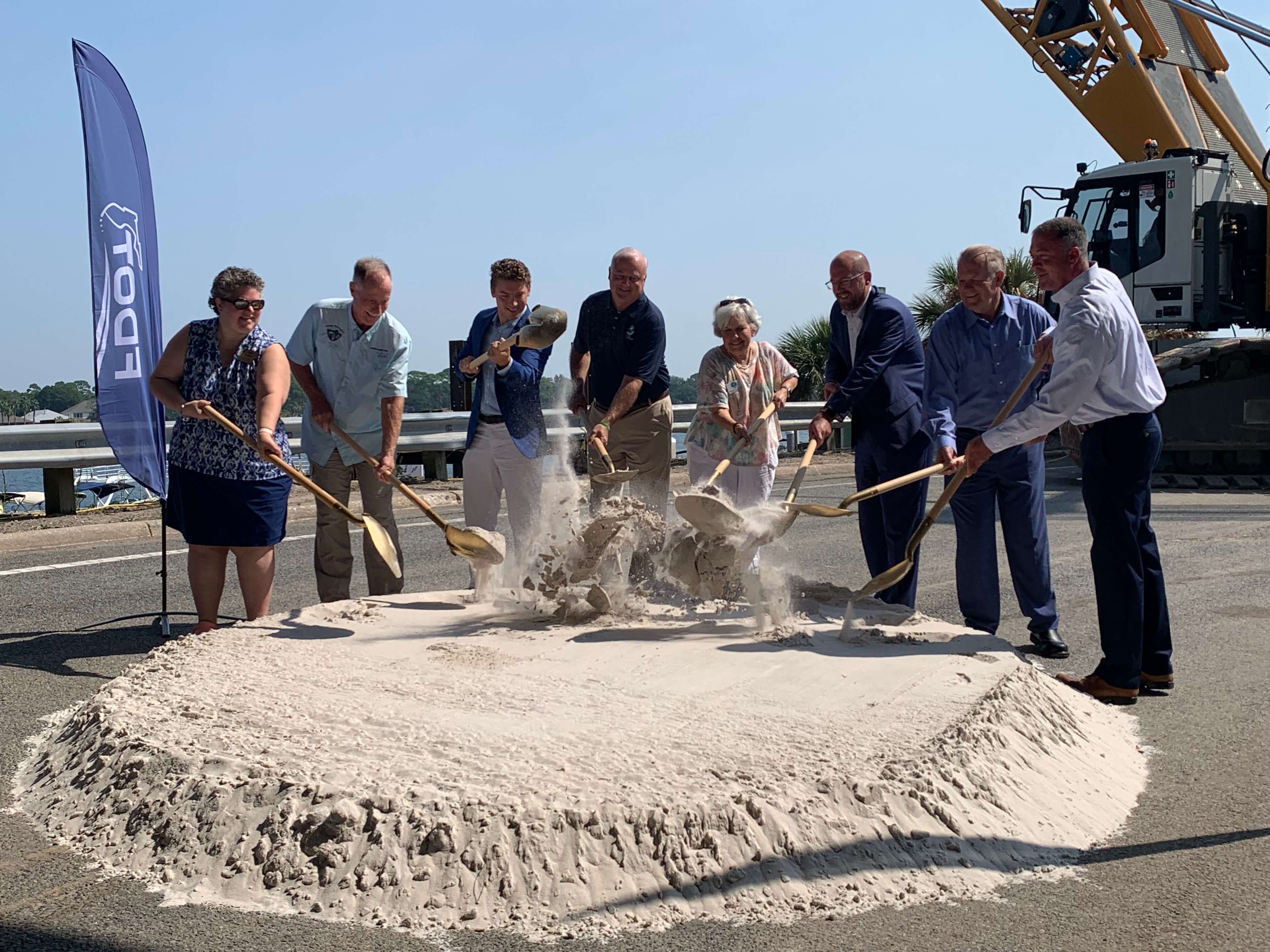 A group of people participate in a groundbreaking ceremony.